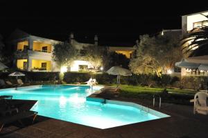 a swimming pool in front of a building at night at Niki Hotel Apartments in Ialysos