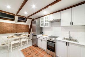 a kitchen with white cabinets and a sink and a table at Cracow Rent Apartments - spacious apartments for 2-7 people in quiet area - Kolberga Street nr 3 - 10 min to Main Square by foot in Krakow