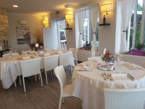 una sala da pranzo con tavoli bianchi e sedie bianche di Villa Lussana a Teolo