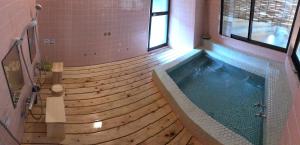 a swimming pool with a wooden floor and a tub at Pension Lanpou in Fujikawaguchiko