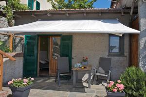 a patio with a table and a white umbrella at Agriturismo OlivArancio in Leivi