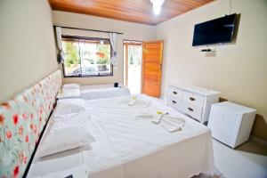 a bedroom with a white bed and a television at Vila Noah Pousada in Paraty +31 photos