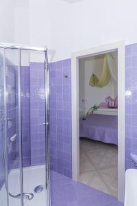 ein Bad mit einer Dusche mit lila Fliesen in der Unterkunft Merydamy in Mattinata
