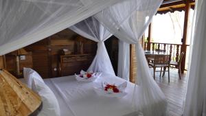 Un dormitorio con una cama blanca con flores. en Lakaz An Bwa en La Digue