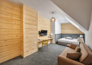 a bedroom with a bed and a couch and a desk at Hotel Gazdówka Spa in Osielsko