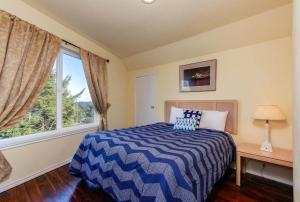 Schlafzimmer mit einem blauen und weißen Bett und einem Fenster in der Unterkunft Seal Three Condo Getaway in Lincoln City