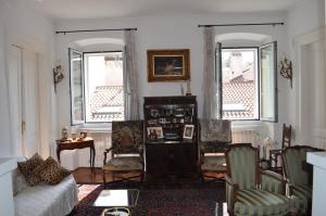 a living room with a couch and chairs and two windows at UNICA nel cuore storico di Trieste in Trieste