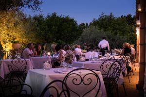 een groep mensen die aan tafels zitten met witte tafelkleden bij Masseria Degli Ulivi in San Corrado di Fuori