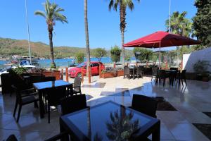 ein Restaurant mit Tischen und Stühlen und einem roten Regenschirm in der Unterkunft Q&S Cennet Life Hotel in Fethiye