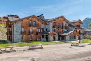 a large wooden building with benches in front of it at Le Refuge in La Rosière