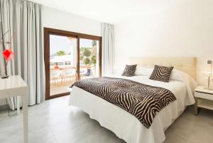 a white bedroom with a bed and a balcony at Casa Munich in Ses Salines +216 photos