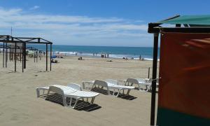 a beach with chairs and a play structure and the ocean at Playa 1 in Villa Gesell