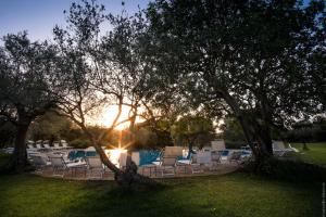 a group of chairs and a pool with the sun setting at Masseria Degli Ulivi in San Corrado di Fuori