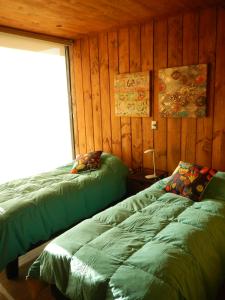 2 letti verdi in una camera con pareti in legno di Cabañas Rincon de Pupuya a Matanzas