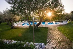 a stone path leading to a pool with chairs and a tree at Masseria Degli Ulivi - Noto in Noto +71 photos