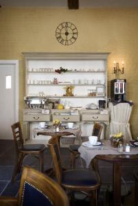 una sala da pranzo con tavoli, sedie e un orologio sul muro di Auberge 's Gravenhof a Voeren