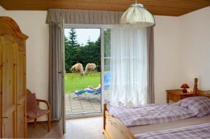 a bedroom with a bed and a sliding glass door with horses outside at Ferienwohnung Hopfennest in Bischofsgrün