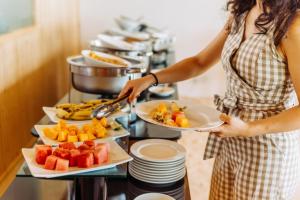 a woman holding two plates of food on a buffet at WAVE SOUND by 3S Maldives in Maradhoofeydhoo