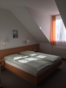 a bed sitting in a room with a window at Hotel garni Zur Mühle in Angermünde