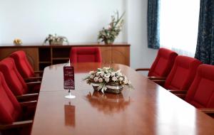 a conference room with a table and red chairs at Hotel Vidović in Banja Luka