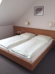 a bed in a bedroom with two lamps on the wall at Hotel garni Zur Mühle in Angermünde