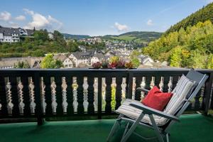 una silla blanca con una almohada roja en el balcón en Café Alt Willingen, en Willingen