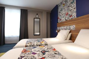 ラヴァルにあるベストウエスタン ホテル ドゥ パリのベッド2台と鏡が備わるホテルルームです。