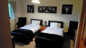 a room with two beds and a chair and pictures on the wall at Bluebell Cottage in Tarbert