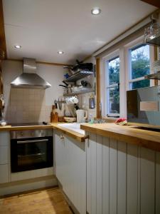 cocina con armarios blancos, fregadero y ventana en Wayside Cottage en Beaulieu