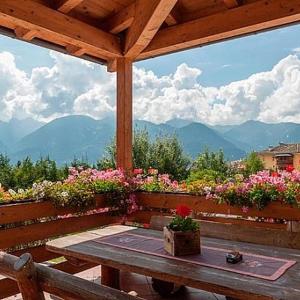 a picnic table with a view of mountains and flowers at Hotel Alla Rocca in Varena