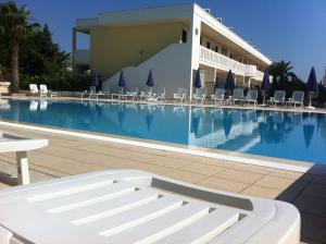 a swimming pool with chairs and a building at Residence Oasi Salento in Torre dell'Orso