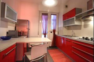 アルバにあるCorso Langhe 27 Albaのキッチン(赤いキャビネット、カウンタートップ付)
