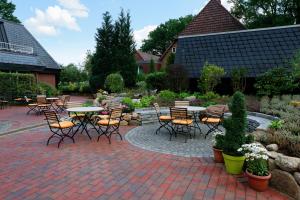 a patio with tables and chairs in a garden at Hotel Sellhorn, Ringhotel Hanstedt in Hanstedt