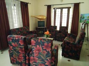 a living room with a couch and chairs and a tv at Birds Nest Home Stay in Cochin