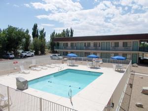 una piscina con sillas y sombrillas frente a un edificio en Motel 6-Green River, UT, en Green River