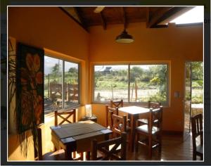 a dining room with a table and chairs and windows at El Mundo Interior in Capilla del Monte