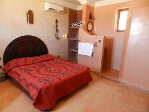 - une chambre avec un lit rouge et un réfrigérateur dans l'établissement Borj Biramane, à Icht