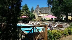 a pool with chairs and umbrellas and a house at manoir du Rieu in Saint-Geniès