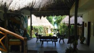 een patio met een tafel en stoelen en een rieten parasol bij Villas Eco-Románticas Kúuch Ka´anil in Bacalar