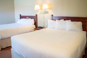 2 Betten in einem Hotelzimmer mit weißer Bettwäsche in der Unterkunft Waterton Lakes Lodge Resort in Waterton Park