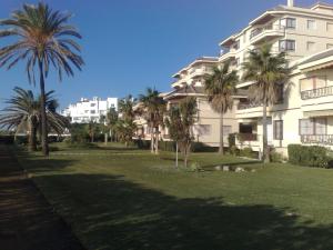 a large building with palm trees in front of it at Urb. Lubina Sol in Mijas Costa