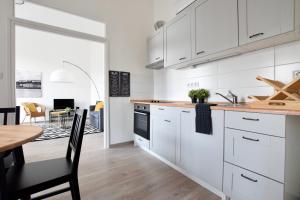 a kitchen with white cabinets and a table and a dining room at Standard Apartment by Hi5 - Bazilika Suite in Budapest