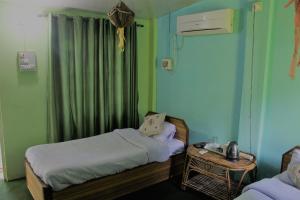 ein kleines Zimmer mit zwei Betten und einem Tisch in der Unterkunft Shuklaphanta Jungle Cottage in Bahāsi