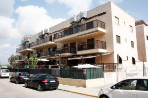 budynek z zaparkowanymi przed nim samochodami w obiekcie Apartamento junto al mar Los Marineros con acceso independiente por terraza w mieście Puzol