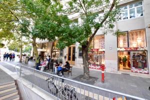 un gruppo di persone seduti su panchine di fronte a un edificio di Standard Apartment by Hi5 - Bazilika Suite a Budapest