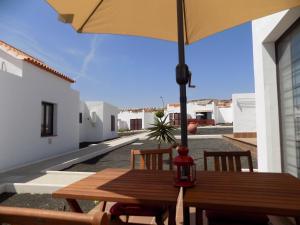 una mesa de madera con una sombrilla en el patio en Sun Beach Bungalows, en Caleta de Fuste