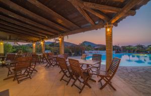 un patio con tavoli e sedie accanto a una piscina di Porto Koukla Beach a Lithakia