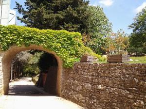 an ivy covered stone wall with an arch way at Domaine Saint Andrieu in Greffeil