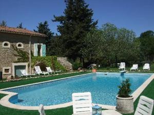 a swimming pool with white chairs and a house at Domaine Saint Andrieu in Greffeil
