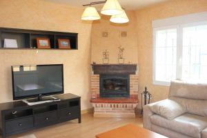 ein Wohnzimmer mit einem Kamin und einem Flachbild-TV in der Unterkunft La Verdevilla in Anguix
